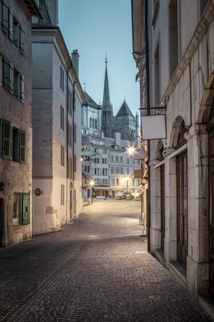 Vue de la place du Bourg-de-Four et de la cathédrale Saint-Pierre depuis la rue Etienne-Dumont à l'aube.