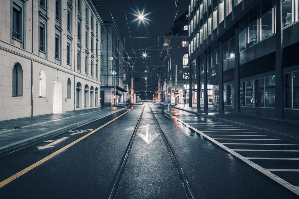 Rues du centre-ville de Genève par nuit pluvieuse : Voies de tramway dans le quartier des Banques.