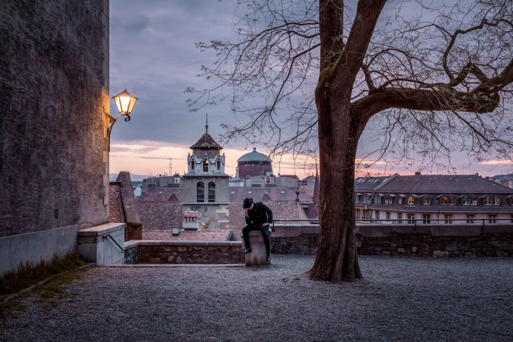 Vieille-Ville de Genève au printemps au lever du soleil, à la terrasse d'Agrippa d'Aubigné, avec un homme en noir portant un chapeau.