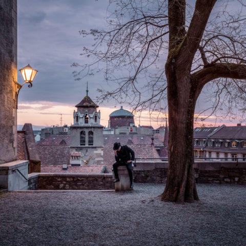 Lever de soleil sur la Vieille-Ville de Genève, vue depuis la terrasse d'Agrippa d'Aubigné avec un homme mystérieux en chapeau noir.