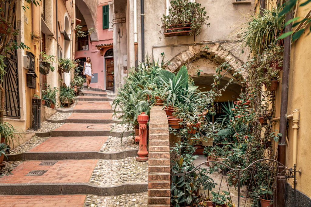 Beau jardin et une jeune fille descendant le long d'une ruelle de la vieille ville de Sanremo, La Pigna.