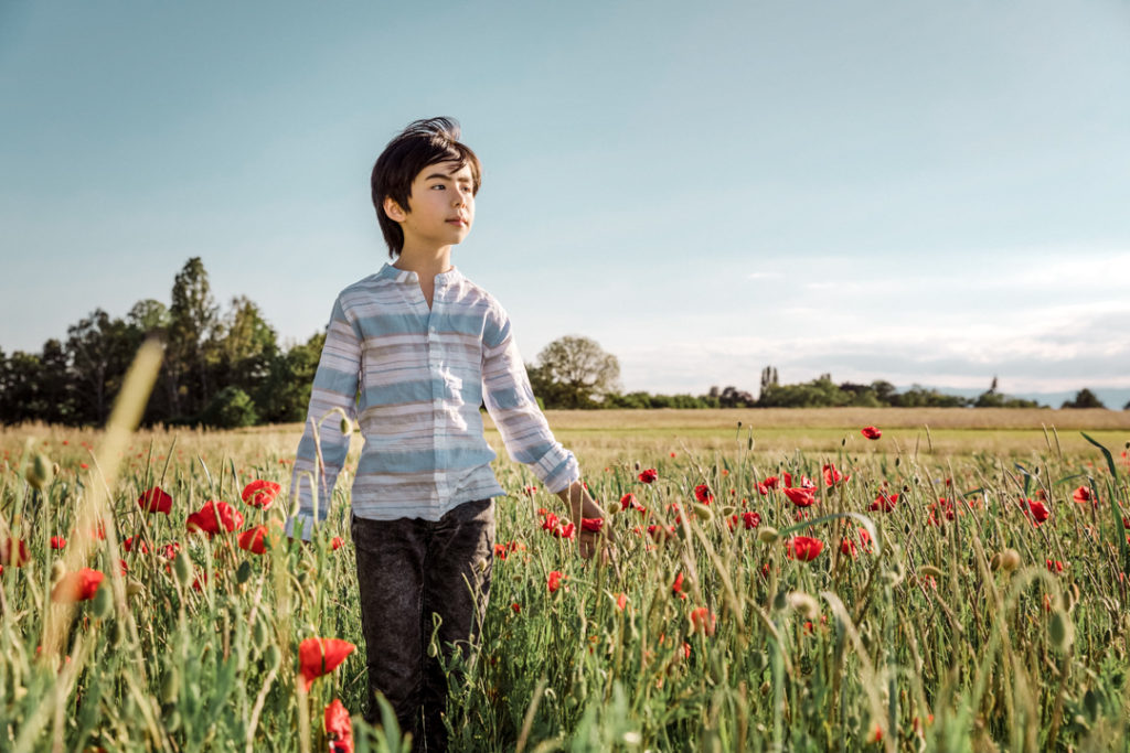 Garçon marchant dans un champ de coquelicots à Genève, printemps 2019.