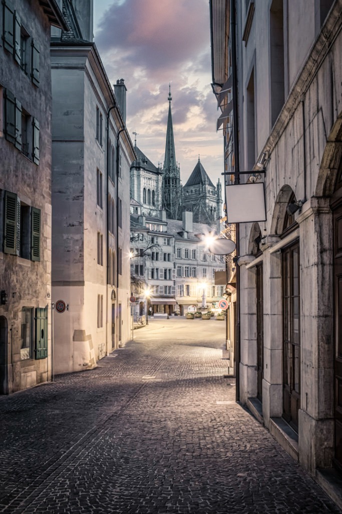 Vue de la place du Bourg-de-Four et de la cathédrale Saint-Pierre depuis la rue Etienne-Dumont à l'aube.