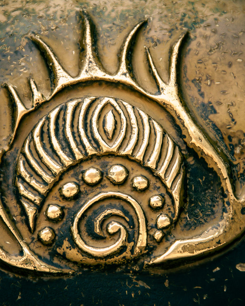 Symbole de feu ou soleil sculpté sur un objet en métal cuivré