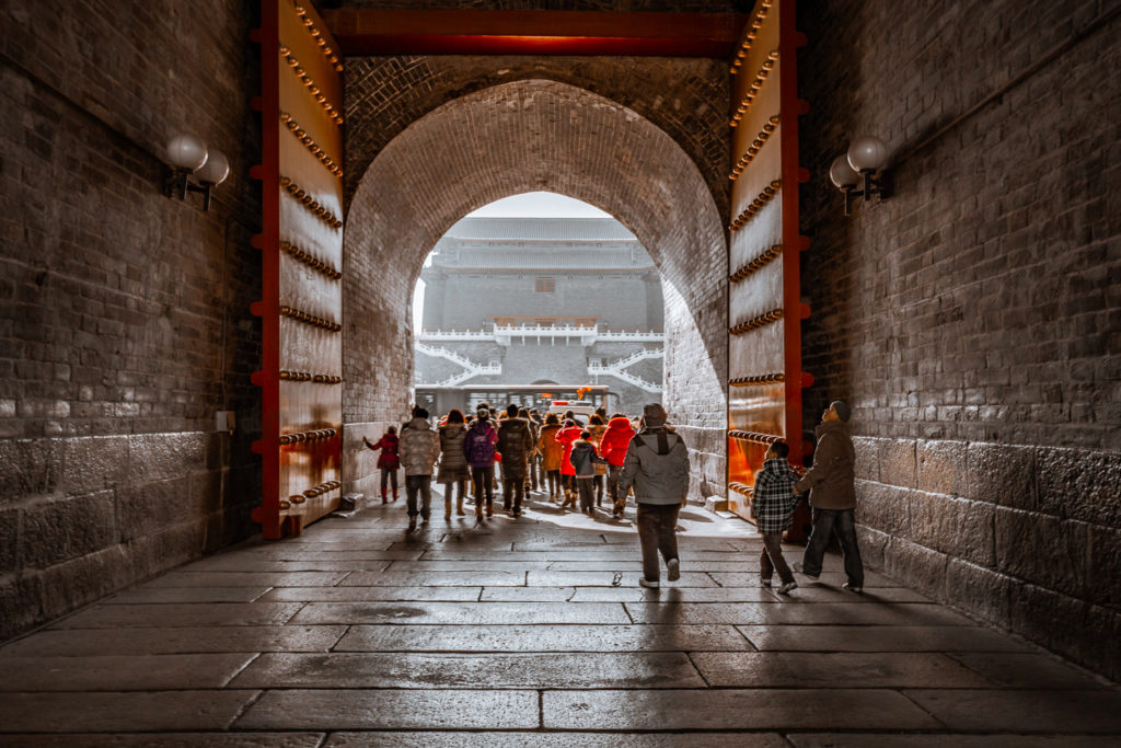 Crowd moving from the shadows of Zhengyangmen Jian Lou towards the light, Beijing, February 2011.