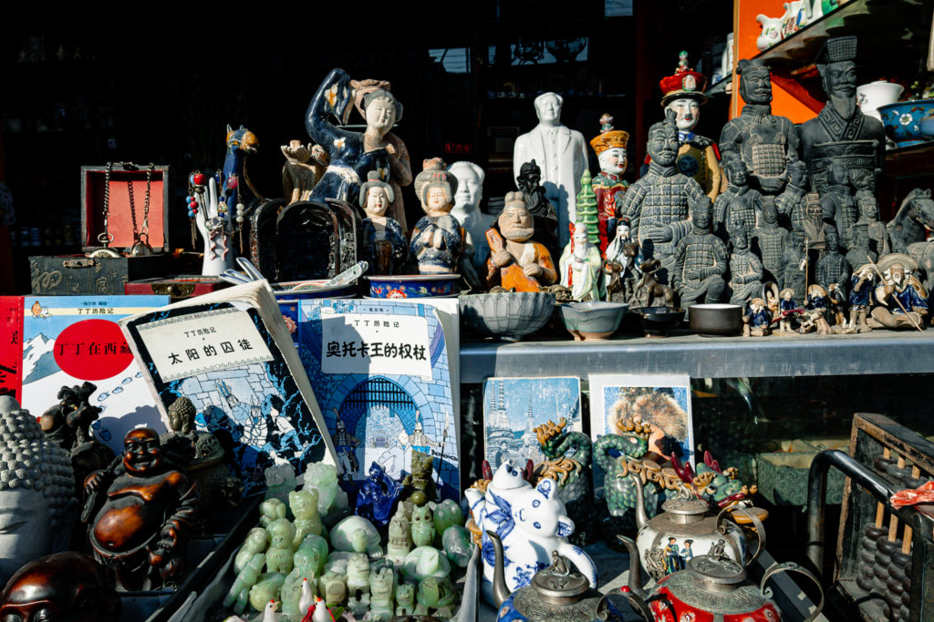  A myriad of Chinese artifacts displayed in the window of an antique shop at Liu Li Chang Dong Jie, showcasing a blend of historical epochs through various objects.